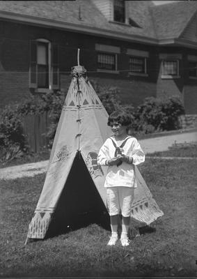 a child in a sailor outfit (appears to be the same child as in item #6,7, and 10) standing in front of a teepee