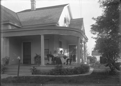 possibly a family (a large group of people with varied ages) sitting on the front porch together