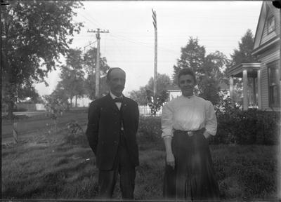 a man and woman standing together in a yard