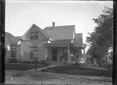 exterior of a house and a woman standing in the yard to the side of house