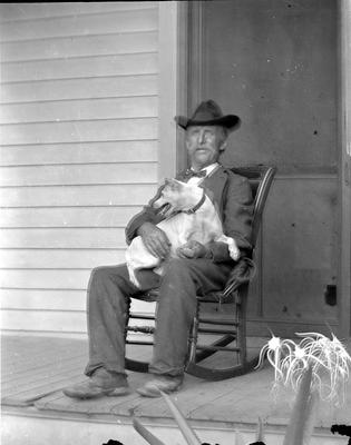 man sitting on the porch in a rocker with a dog