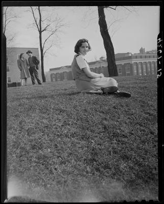 Katherine Parch sitting on the lawn, unidentified man and women                             standing in the background; (1940 Kentuckian) (University of                             Kentucky)