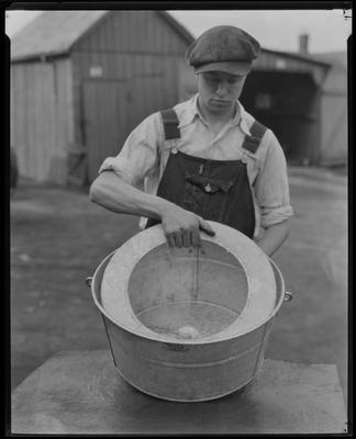 Man in overalls, holding large metal tub