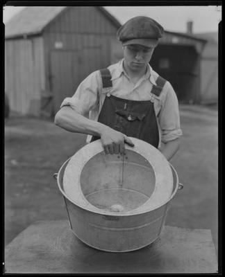 Man in overalls, holding large metal tub