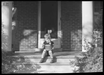 Young boy sitting on porch steps