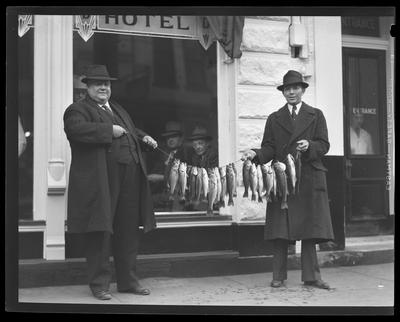 Two men holding string of fish