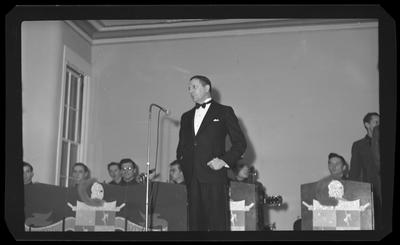 Man in tuxedo, in front of mic stand