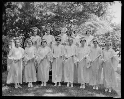 Young women in caps and gowns, holding diplomas