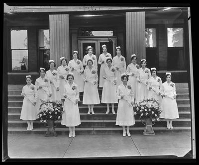 16 young women, all holding diplomas