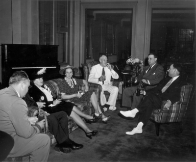 Four men and two women sitting in hotel lobby with refreshments