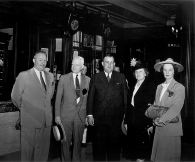 Three men and two women standing in a hotel lobby