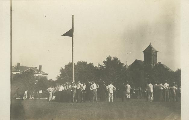 flag with group of boys gathered around the flag pole circa 1910