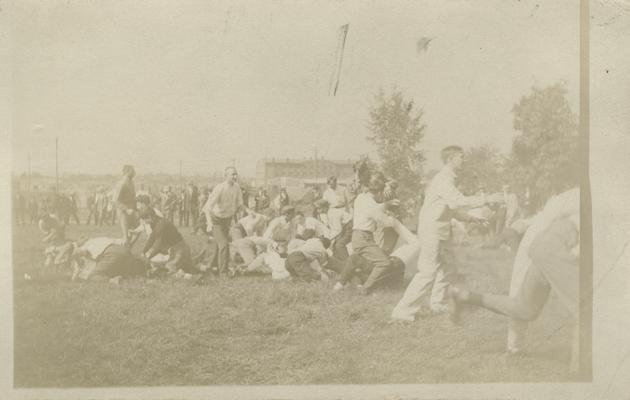 men wrestling on the ground, and running around circa 1910