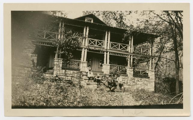 Idle Wild cabin with men and women sitting on front stone steps, Kentucky River