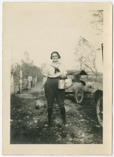 Marietta Eichelberger, now of Chicga holding three buckets next to two automobiles