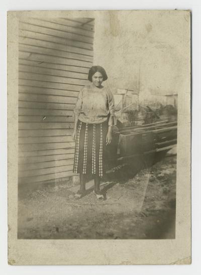 Earnestine E. Wilson standing in front of the side of a house, note on back says My wife Earnisteen [sic] E. Wilson. Central City