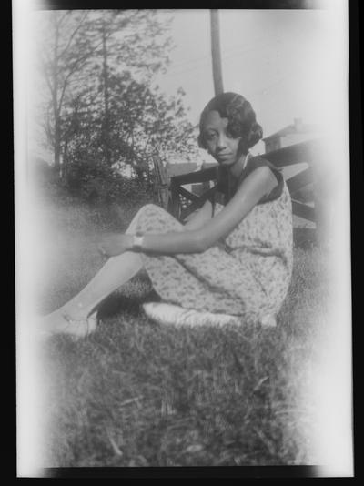 Negative of an unidentified woman sitting in the grass