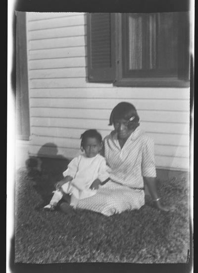 Negative of unidentified woman and child in yard