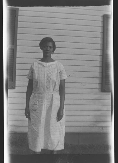 Negative of an unidentified woman in front of the side of a building