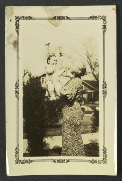Unidentified woman lifting a young child into the air