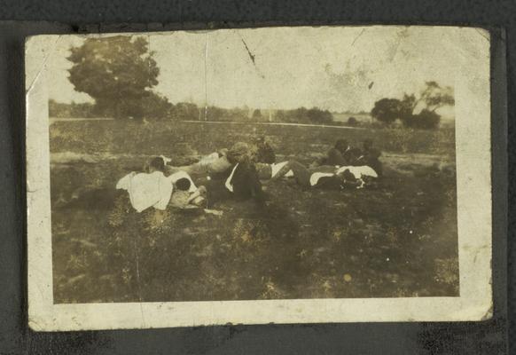 Page 1 [R]: Group of unidentified black men and women laying down in a field