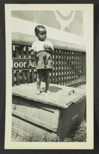 Young unidentified black boy on ice water box