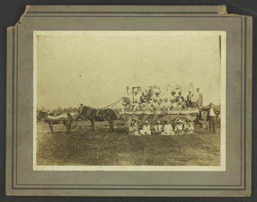 Group photo of unidentified black men, women, and children on mule-drawn wagon adorned with American flag-themed paraphernalia