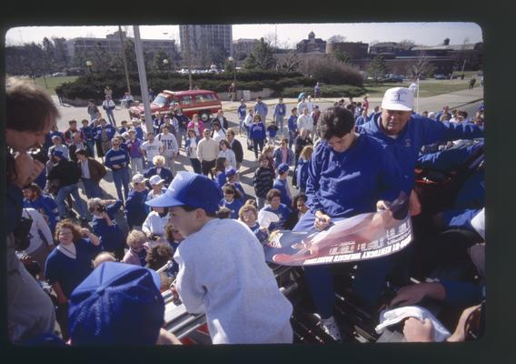 Rick Pitino autographs a poster in UK parade