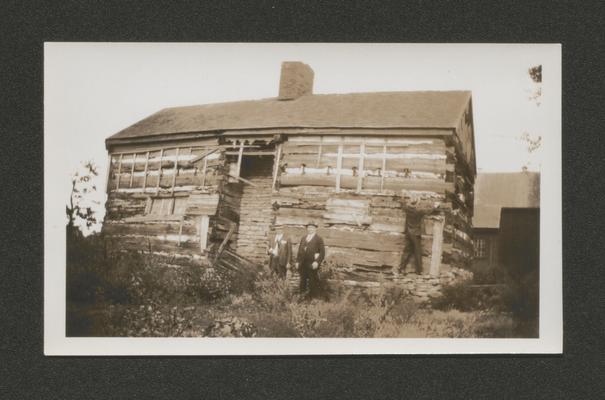 Three men in front of log cabin