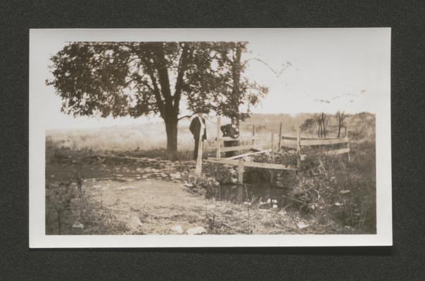 Two men on a small bridge over a creek