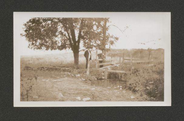 Two men on a small bridge over a creek (Duplicate of #60.)