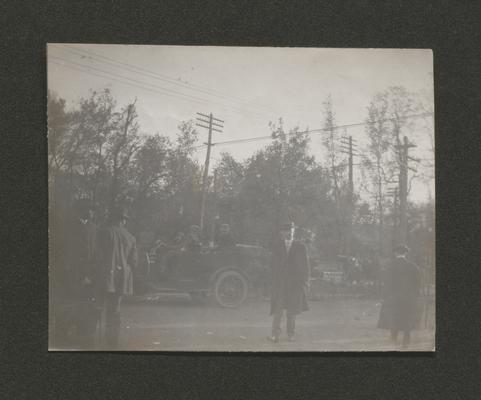 Several men with a car in the background