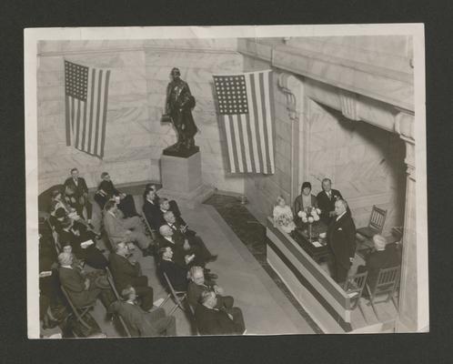 Hall lobby of Capitol Building, crowd listening to a speaker