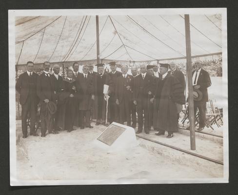 Seventeen men, including Samuel M. Wilson, some in academic robes, gathered around a memorial tablet under a tent