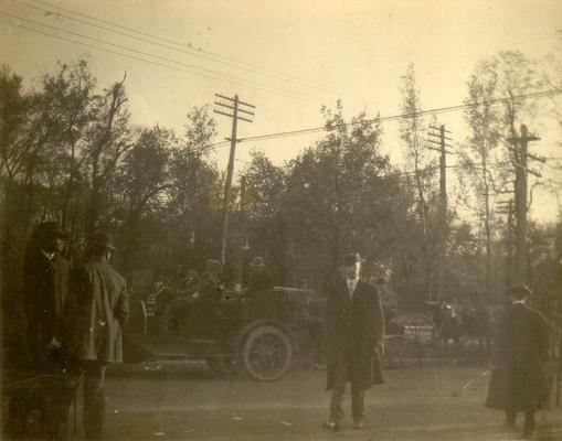 Several men with a car in the background