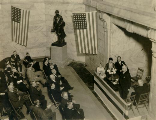 Hall lobby of Capitol Building, crowd listening to a speaker