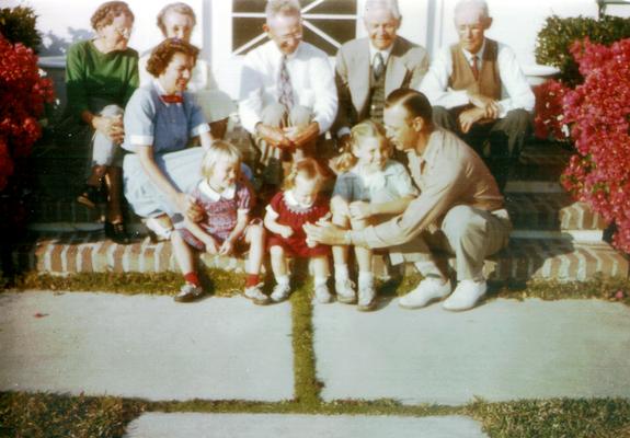 Group of adults and children sitting on porch steps (Color photo)