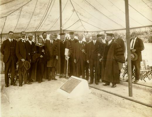 Seventeen men, including Samuel M. Wilson, some in academic robes, gathered around a memorial tablet under a tent