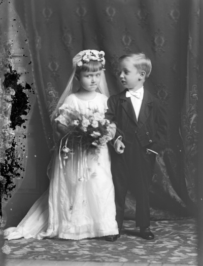 Full length group portrait of a standing boy and girl holding hands, identified as 