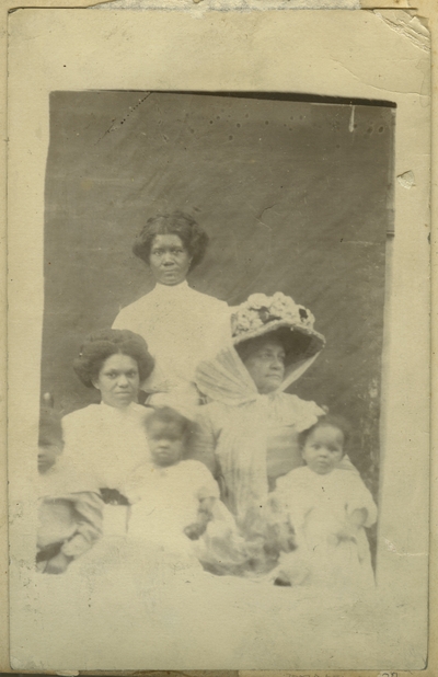 Three unidentified African American females and two unidentified African American children ; photo remains within album and is located on page 28