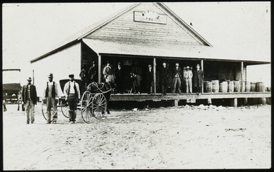 Group of men standing outside of a wooden building