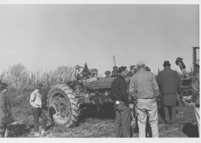 Series S- S10: Glensboro (Ky.), bidders at auction standing around tractor