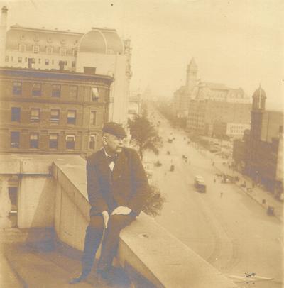 Thomas Howe Ridgate: to my esteemed friend Mr. Samuel Wilson. Sept 14, 1907. Ridgate sitting on wall on roof of building overlooking a city