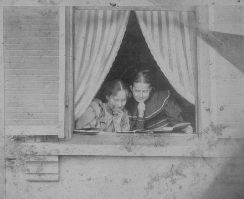 Two young women at a window reading, members of the Shelby family