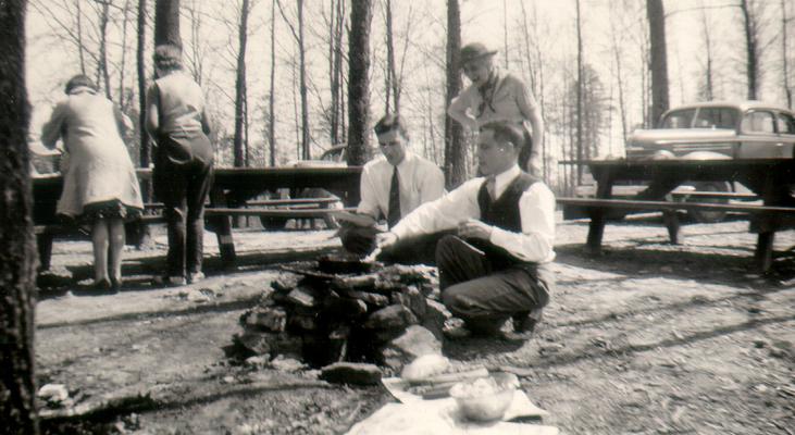 Three men cooking on an outdoor fire