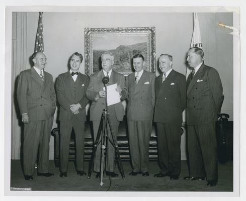 Secretary of the Treasury Vinson with recipients of Treasury's Silver Medal for Distinguished Service in War Finance, 1941-45. Left to right: Edmund Reek, Twentieth Century-Fox Movie News; Walton C. Ament, RKO Pathe News; Secretary Vinson, reading the citation; Thomas Mead, Universal Newsreel; Michael D. Clopine, MGM News of the Day; and E.P. Genock, Paramount News