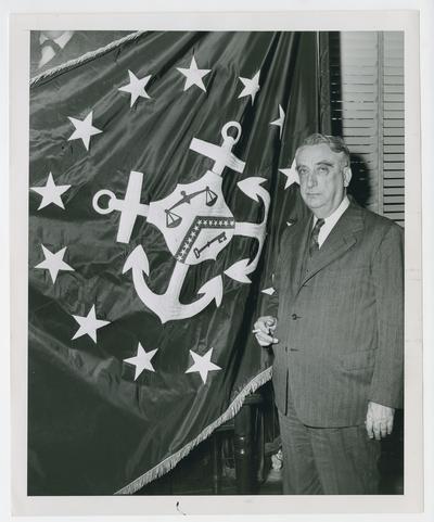 Secretary Vinson next to Department of the Treasury flag