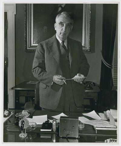 Secretary Vinson stands behind his desk