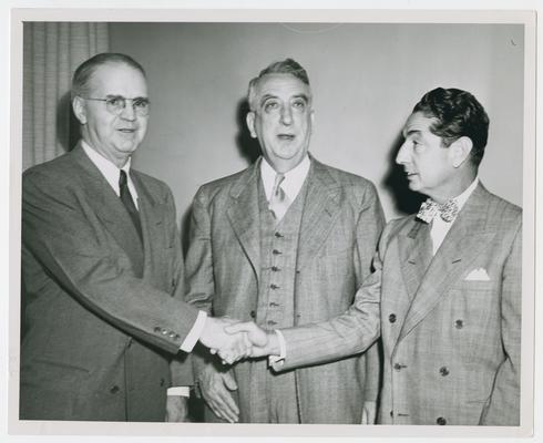 Secretary Vinson behind two unidentified men in handshake
