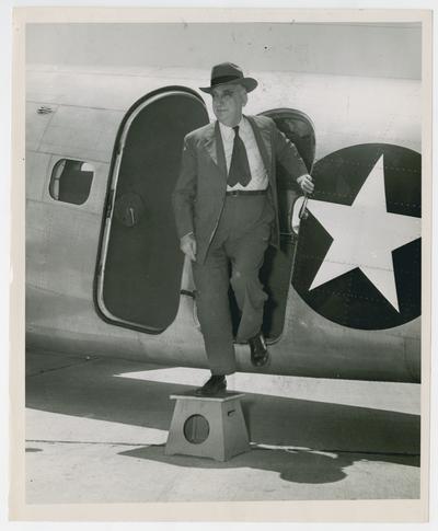 Secretary Vinson steps from airplane door, Lexington, Kentucky